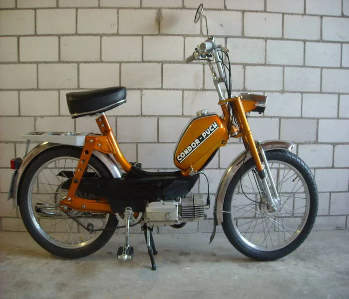 Puch Condor von 1970 in Orange mit Condor-Puch-Schriftzug auf dem Tank, vor weisser Backsteinwand